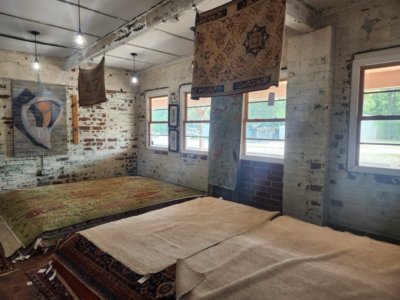 Traditional rugs displayed and hanging inside the exposed brick interior of the historic depot at Fletcher's Rug Company in Yemassee