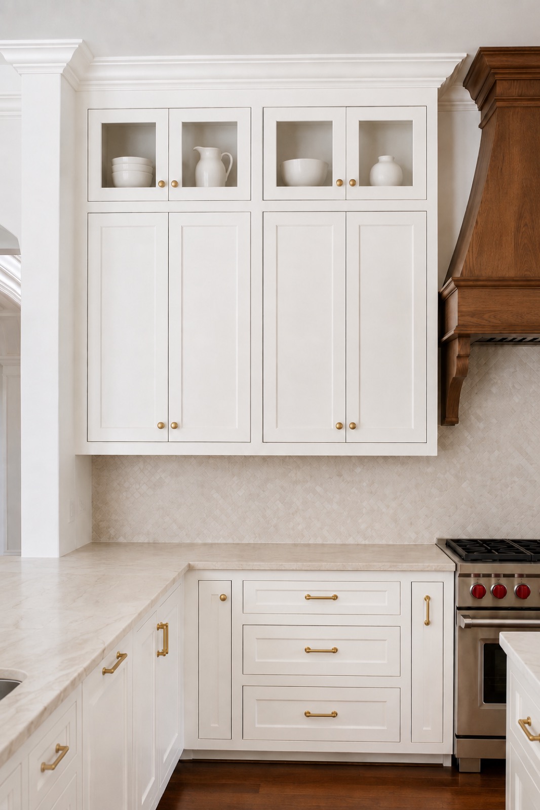 Stacked upper kitchen cabinets with glass fronts above solid cabinet doors and brass hardware